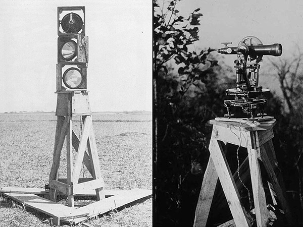 A four-foot stand with three older style signal light and a four-foot stand with an theodolite