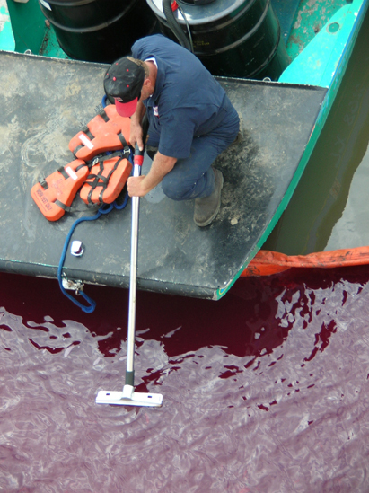responder attempts to contain recently spilled oil with a boom