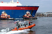 A U.S. Coast Guard vessel escorts an LNG bulk carrier into Boston Harbor. 